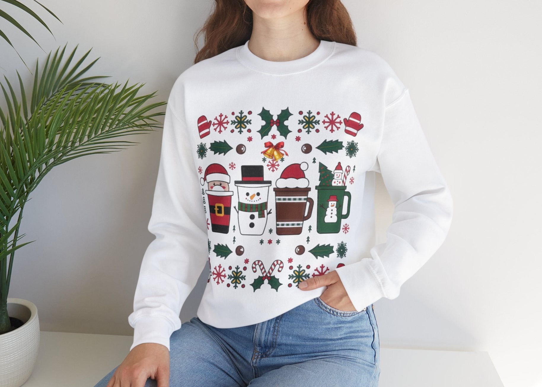 Model wearing a white sweatshirt featuring a festive holiday pattern with coffee cups, snowflakes, and Christmas elements, styled casually. Part of the Vivid Divergence Sensory Friendly Unisex Sweater Jumper Range.
